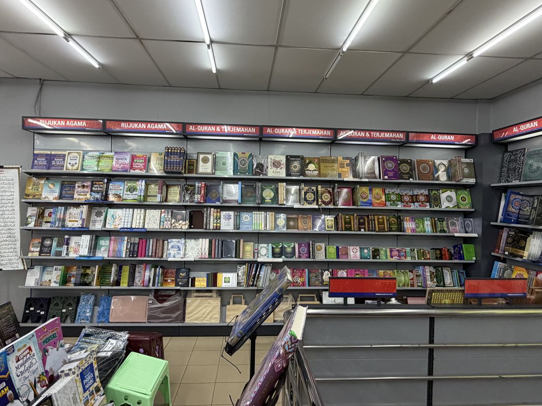 A bookshop wall in Kota Bharu where shelves labelled Al-Quran, translations and religious reference fill almost the whole wall